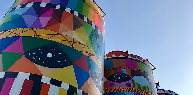 Bunte Graffiti-Kunst auf großen Silos am ÜeberQuell in Hamburg bei blauem Himmel.