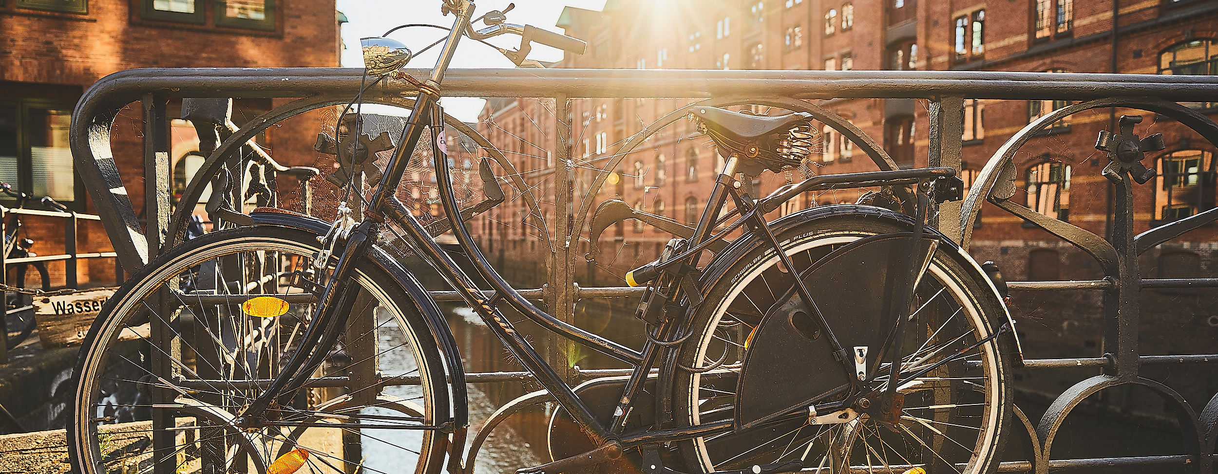 Fahrräder auf Brückengeländer vor historischer Backsteinarchitektur in der sonnigen Speicherstadt