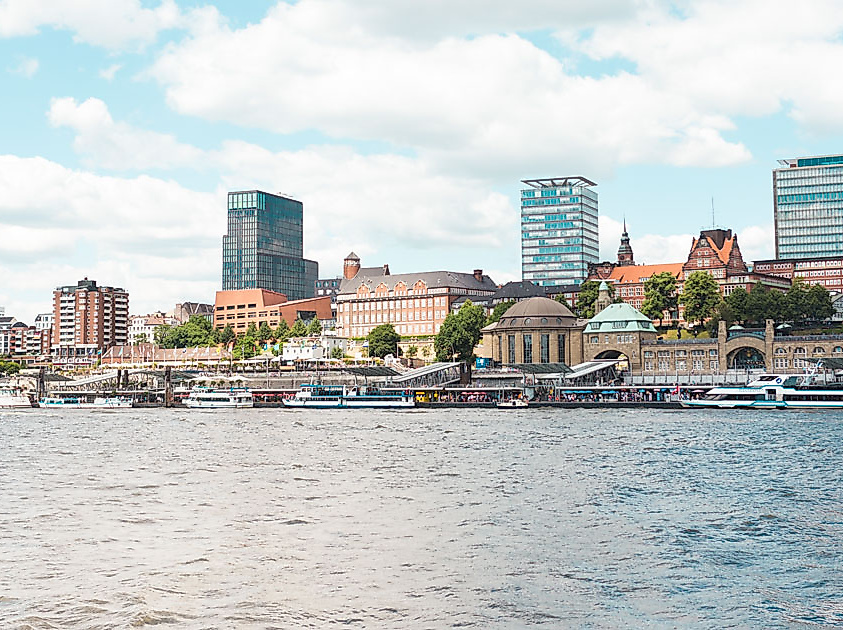 Stadtpanorama von Hamburg mit Landungsbrücken, modernen Hochhäusern und Wasserblick bei teils bewölktem Himmel