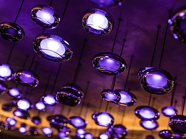 Moderne Deckenbeleuchtung mit violett leuchtenden Spots schafft clubartige Atmosphäre in Pop-Club.