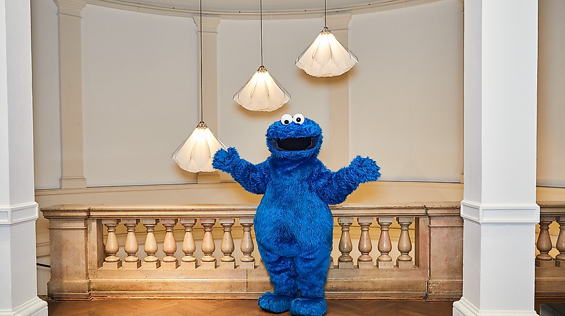 Das Krümelmonster posiert im Museum für Kunst und Gewerbe Hamburg unter dekorativen Hängelampen