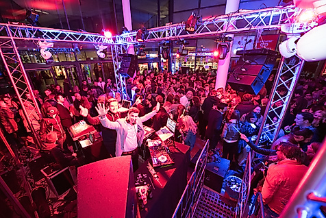 DJ-Pult mit Plattenspielern in der Sunset Lounge Disco, umgeben von buntem Licht und Partystimmung