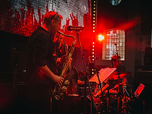 Livemusik in rotem Licht: Saxofonist spielt auf kleiner Bühne in stimmungsvoller Bar-Atmosphäre