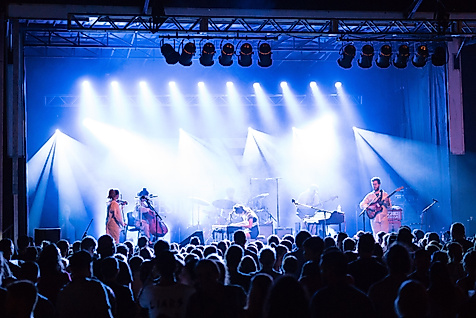 Publikum vor hell beleuchteter Bühne bei Live-Konzert mit Band und Scheinwerfern