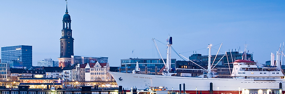 Cap San Diego im Hamburger Hafen bei Abendlicht mit Blick auf den Michel und die Stadt