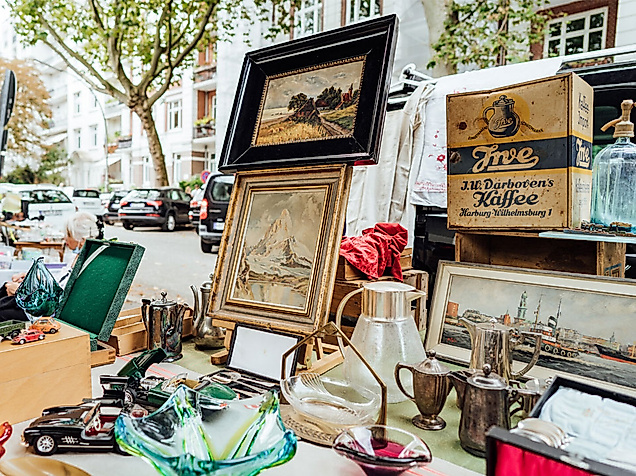Flohmarktstand an der Isestraße mit Antiquitäten, Bildern und Trödel unter Bäumen.