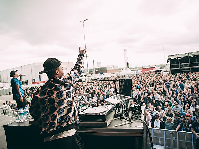 Beginner auf Festivalbühne vor tanzendem Publikum bei Open-Air-Event 