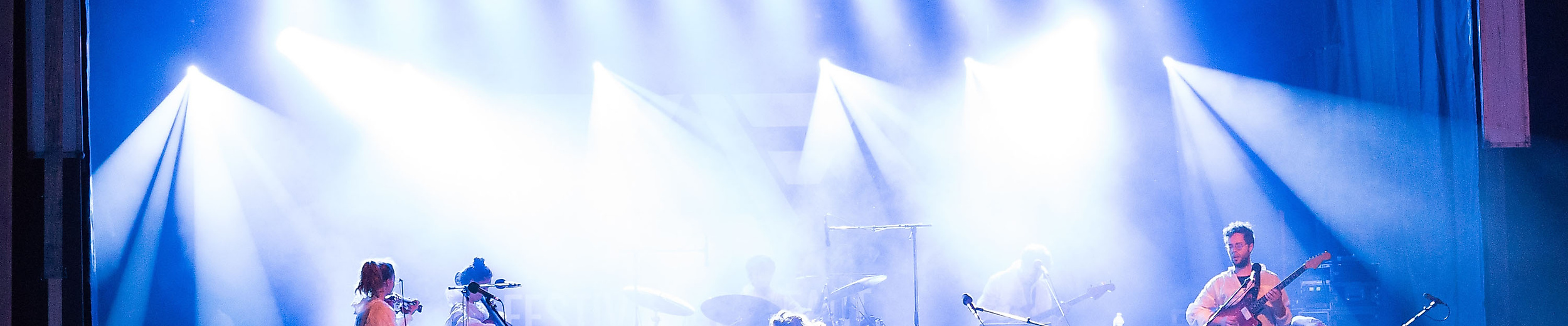 Publikum vor hell beleuchteter Bühne bei Live-Konzert mit Band und Scheinwerfern