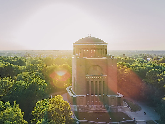 Luftaufnahme des Hamburger Planetariums im Stadtpark bei Sonnenaufgang über dichtem Blätterdach