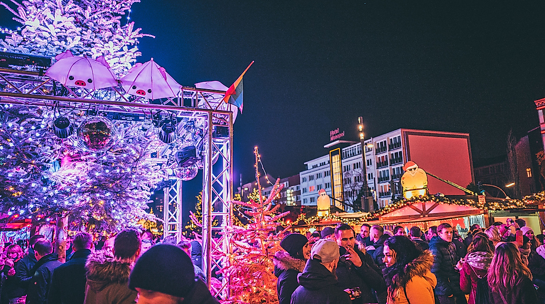 Colorfully illuminated Christmas market with crowds and festive light installation at night