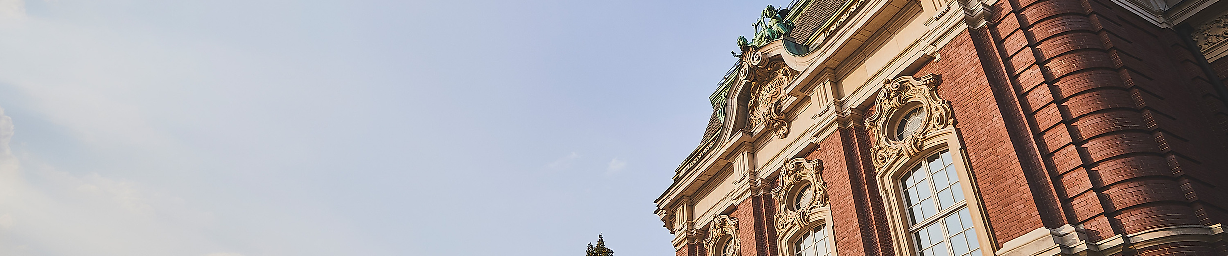 Seitenansicht der Laeiszhalle Hamburg bei Sonnenschein mit Bäumen und blauem Himmel