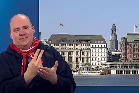 Mann gebärdet vor Panorama der Hamburger Innenstadt mit Alsterarkaden und Michel – barrierefreie Stadtinformationen.