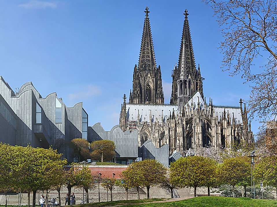 Blick auf den Kölner Dom mit seinen markanten Türmen, links das Museum Ludwig, davor herbstlich gefärbte Bäume.