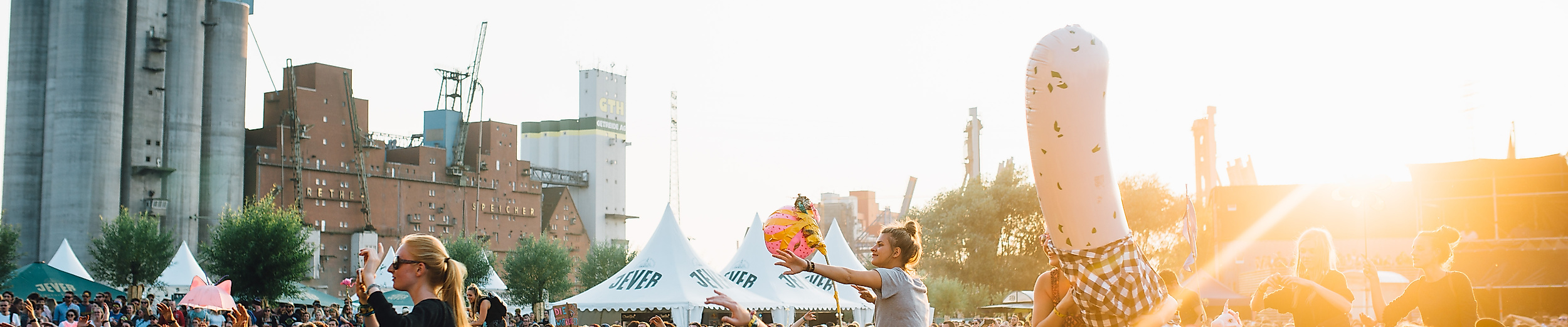 Festivalbesucher:innen beim MS Dockville in Hamburg bei Sonnenuntergang vor urbaner Kulisse