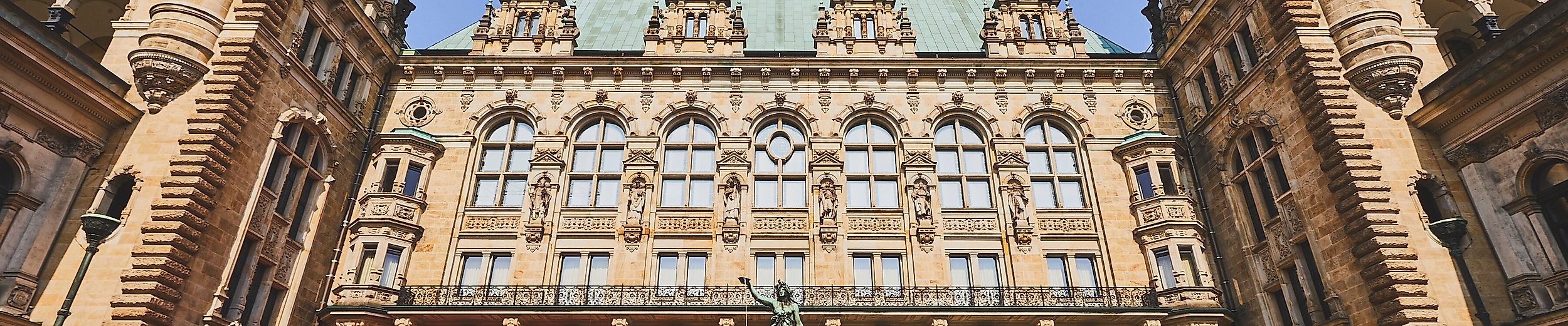 Prächtige Fassade des Hamburger Rathauses mit Innenhof und Arkadengang bei blauem Himmel