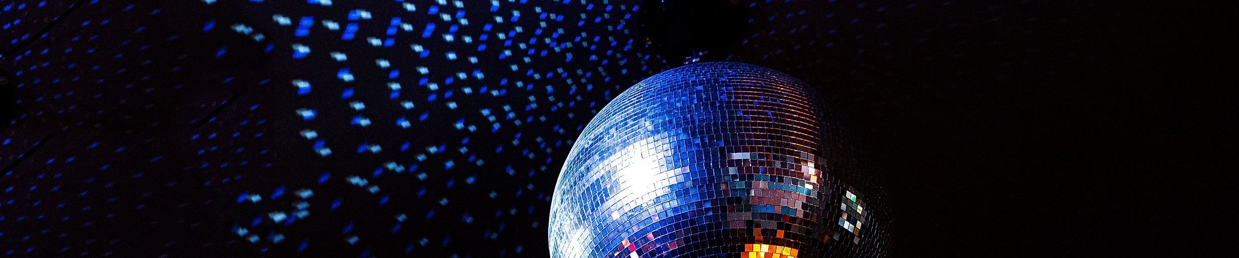 Spiegelkugel im Club wirft blaue und orange Lichtpunkte auf die dunkle Umgebung