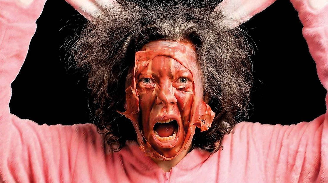 A person with messy hair is wearing a pink bunny costume.
