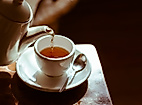 Tee wird in weiße Porzellantasse gegossen, warmes Licht sorgt für gemütliche Atmosphäre bei Tea Tim