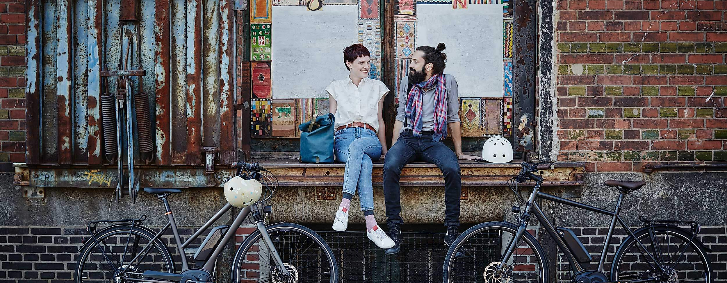 Zwei Personen mit Fahrrädern pausieren vor roter Backsteinfassade in Hamburgs Speicherstadt.