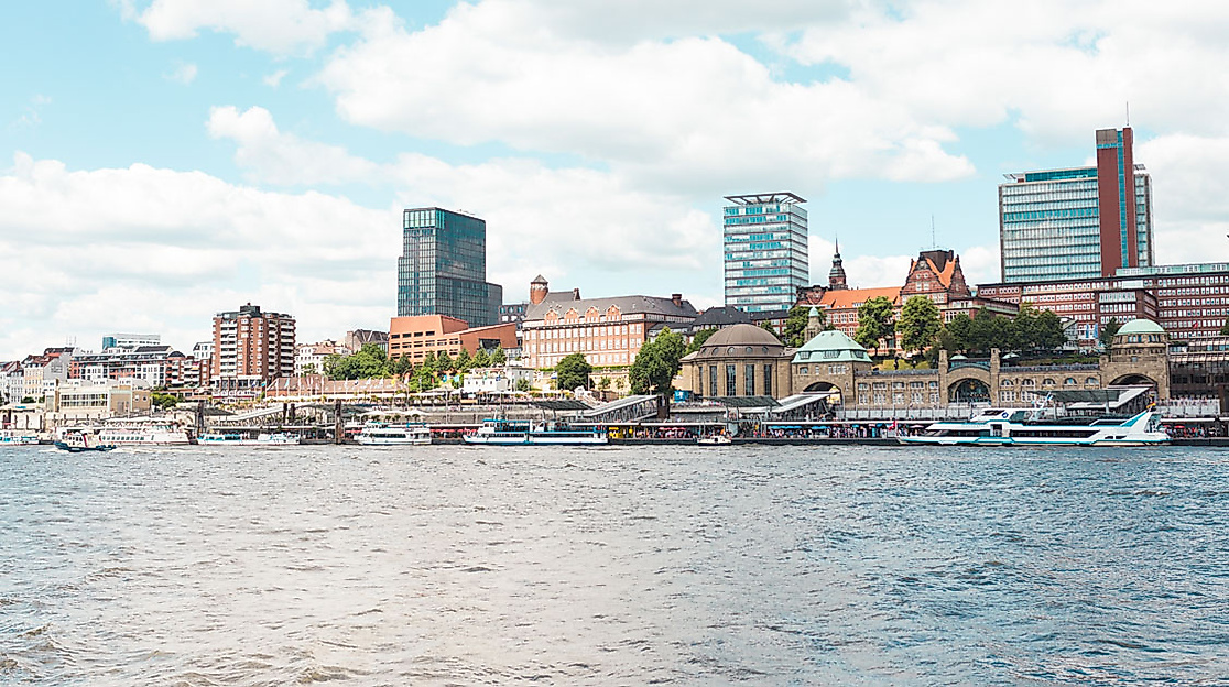 Stadtpanorama von Hamburg mit Landungsbrücken, modernen Hochhäusern und Wasserblick bei teils bewölktem Himmel