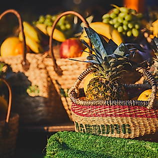 Geflochtene Körbe mit frischem Obst wie Ananas, Trauben und Bananen auf dem Hamburger Fischmarkt