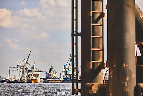 Industrielle Hafenansicht in Hamburg mit rostiger Leiter im Vordergrund und Kränen im Hintergrund