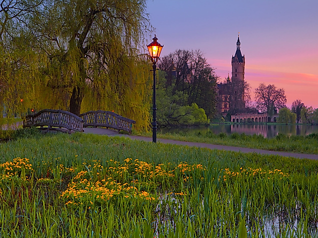 Blühende Schlosswiese mit Laterne im Abendlicht, im Hintergrund das Schweriner Schloss