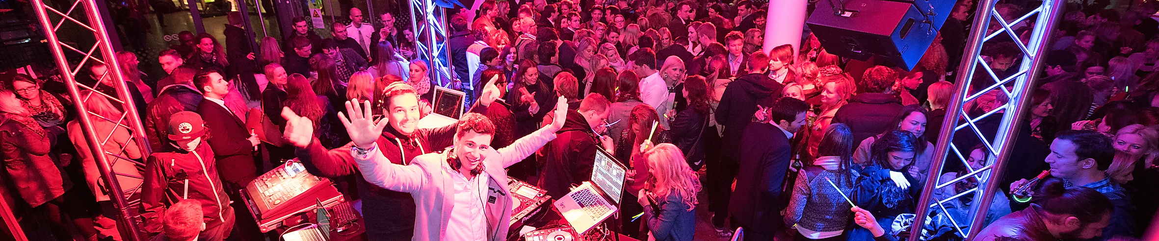 DJ-Pult mit Plattenspielern in der Sunset Lounge Disco, umgeben von buntem Licht und Partystimmung