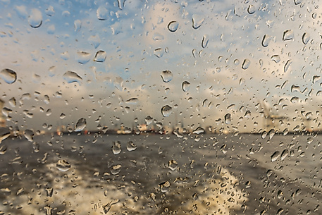 Blick durch regennasse Fensterscheibe auf die Elbe bei windigem Wetter in Hamburg