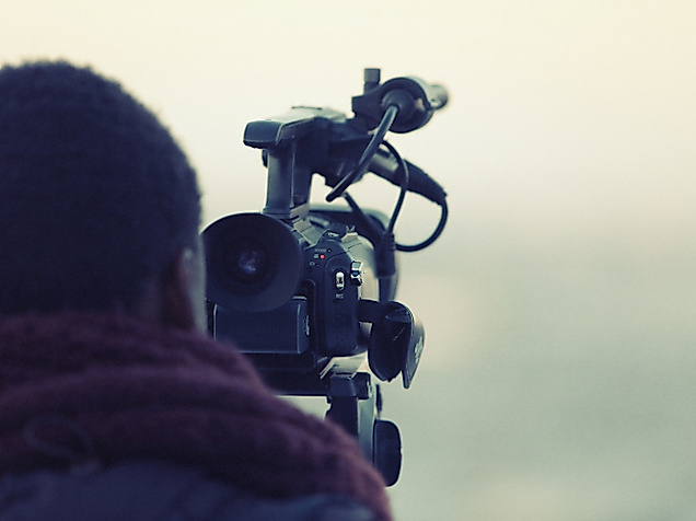 Person mit Kamera beim Filmen im Freien, Symbol für Hamburg als Filmstadt