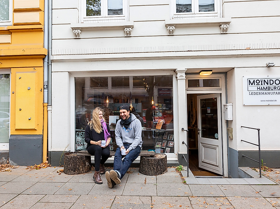 Atelier MoinDori in Hamburg mit zwei Personen auf der Bank vor dem Eingang und kreativem Schaufenster