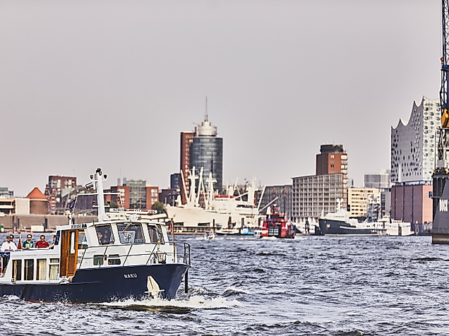 Hafenboot auf der Elbe vor Kulisse des Hamburger Hafens mit Kränen und Hafengebäuden