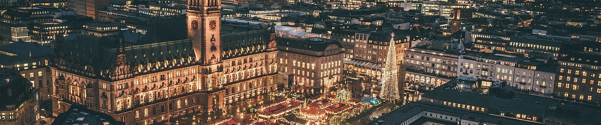 Luftaufnahme der festlich beleuchteten Hamburger Innenstadt mit Weihnachtsmarkt am Rathaus bei Nacht