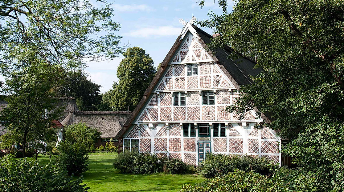 Typisches Fachwerkhaus mit Reetdach im Alten Land bei Hamburg, umgeben von Obstbäumen und Garten