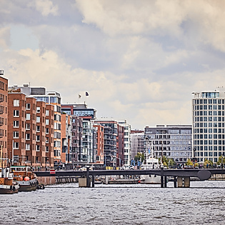 Backsteinfassaden und moderne Gebäude am Fleet in der HafenCity Hamburg mit Brücke im Vordergrund