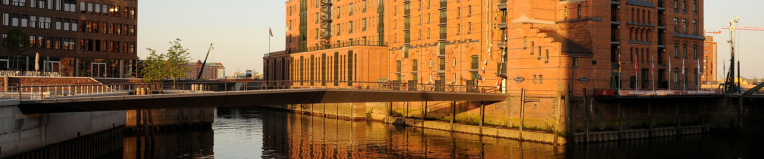 Backsteinfassade des Internationalen Maritimen Museums im Abendlicht mit Spiegelung im Wasser.