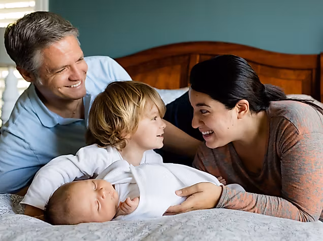 Mann, Frau und zwei Kinder zusammen auf einem Bett