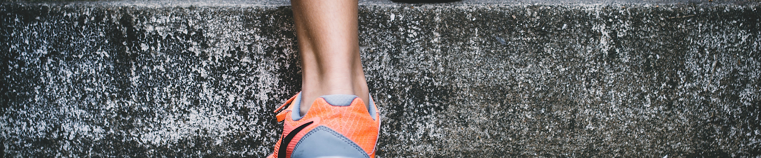  Person mit Sportschuhen läuft eine steinerne Treppe hinauf als Teil eines Lauftrainings.