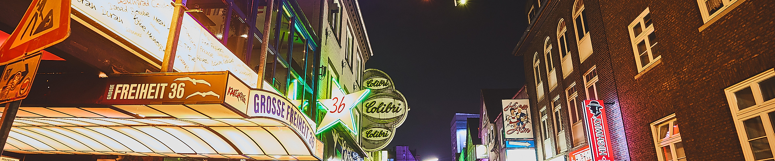 Belebte Große Freiheit auf St. Pauli bei Nacht mit Neonlichtern, Bars und vielen Passant:innen