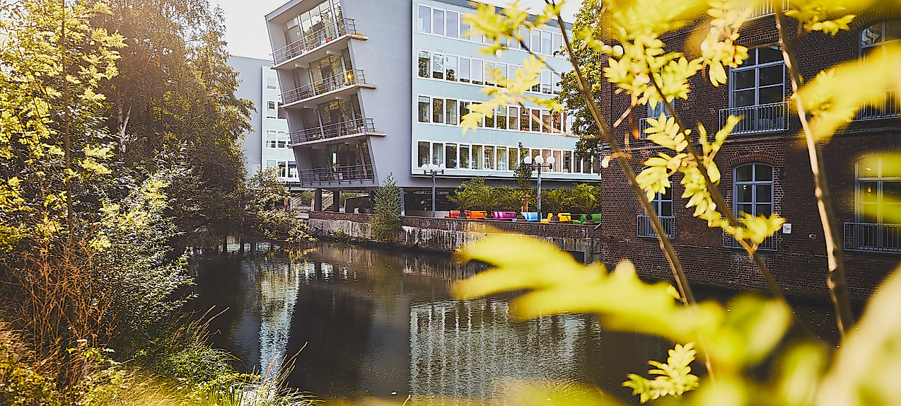 Harburger Theater am Kaufhauskanal in Hamburg, im Sonnenlicht durch Blätter mit Spiegelung im Wasser