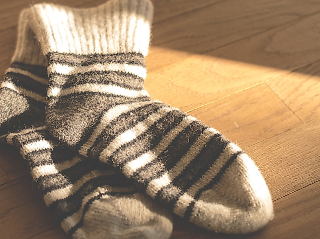 Gestrickte Wollsocken mit Streifenmuster im warmen Licht auf Holzuntergrund in einem Hamburger Shop