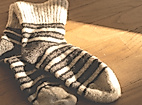 Gestrickte Wollsocken mit Streifenmuster im warmen Licht auf Holzuntergrund in einem Hamburger Shop