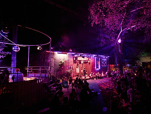 20260814 ISF garten There's a festive atmosphere at the Migrantpolitan. The building is bathed in pink light, and a disco ball hangs over the pool. 0754
