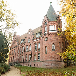 Backsteinbau des Bergedorfer Schloss in Hamburg, umrahmt von herbstlich gefärbten Bäumen und Gartenweg