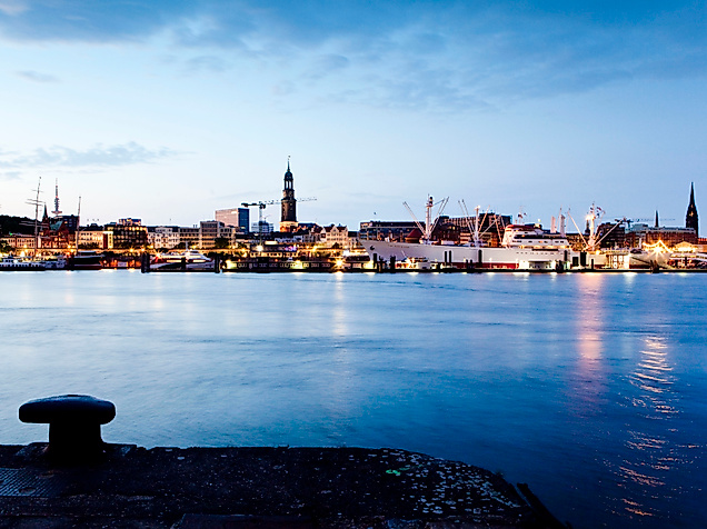 Abendstimmung im Hamburger Hafen mit Lichterspiegelung auf der Elbe und Poller im Vordergrund