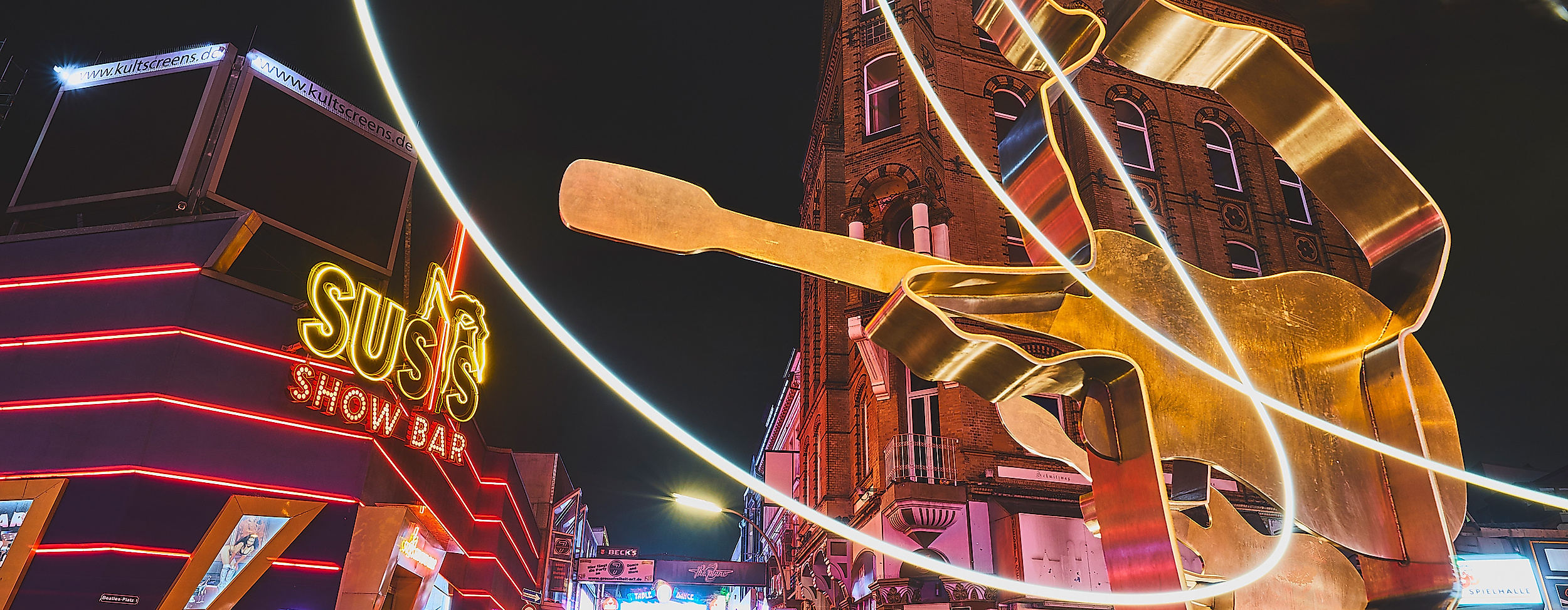 Leuchtende Gitarristen-Skulptur am Beatles-Platz auf der Reeperbahn bei Nacht mit Neonlichtern
