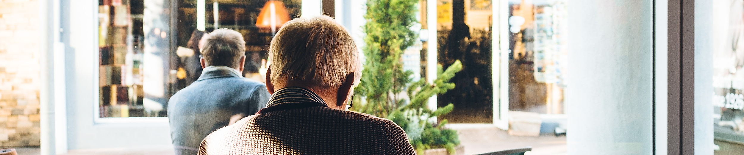 Ältere Person sitzt entspannt im Café am Fenster – ruhiger Moment bei Kaffee in Hamburg