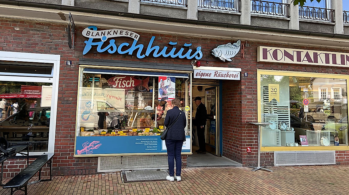 Außenansicht des Blankeneser Fischhuus mit Kund:in vor dem Laden – traditionelles Fischgeschäft in Blankenese