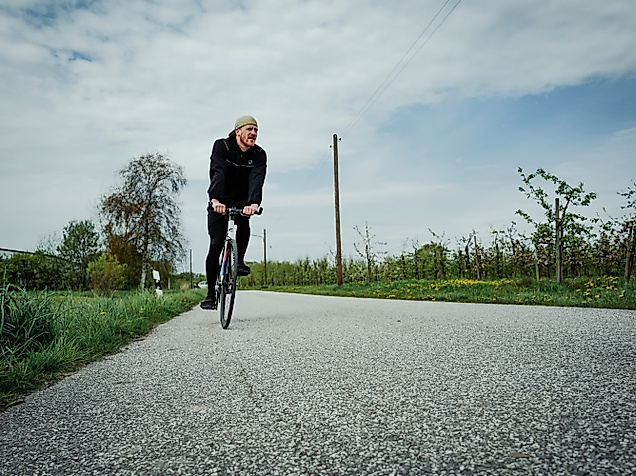 Radfahrer auf einem Feldweg in Finkenwerder, umgeben von Obstbäumen und weitem Himmel