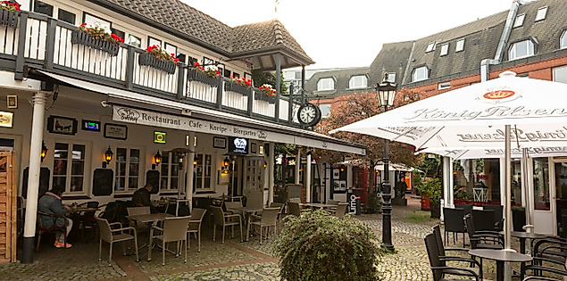 Gastronomiebereich im Suhrhof in Hamburg-Bergedorf mit Fachwerkfassaden, Außenterrasse und Sonnenschirmen im Innenhof.